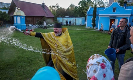 Water spray hangs in the air as priest blesses people 