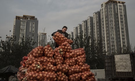A Chinese market worker unloads onions in Beijing. The economy slowed in the third quarter.