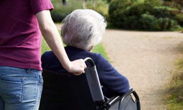 Young woman pushing older woman in a wheelchair.