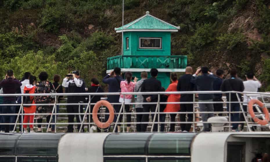  Chinese tourists look and take pictures of a North Korean soldier in a watchtower as they ride on a tourist boat on the Yalu river with North Korean territory on both sides, north of the border city of Dandong, Liaoning province, northern China near Sinuiju, North Korea in Dandong, China. 
