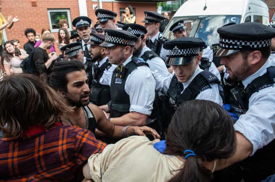 Police hold back activists trying to block an immigration van from transporting a prisoner.