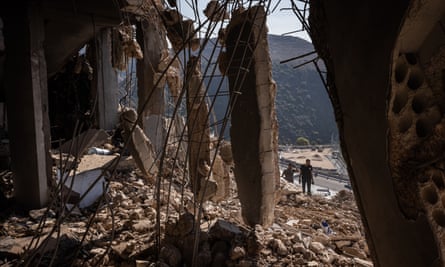 Two rescue workers are seen through an opening in a wrecked building