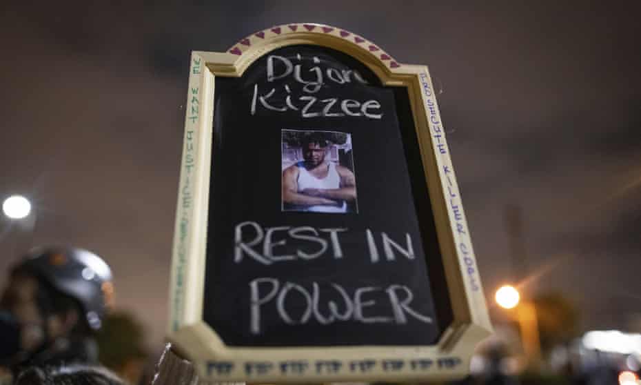 A protester holds a sign with a picture of Dijon Kizzee, who died after being shot by Los Angeles sheriff’s department deputies.