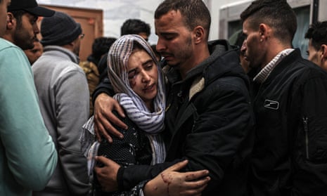 A grieving woman is consoled by a man in a crowded room