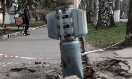 A man walks past an unexploded tail section of a 300mm rocket which appears to contain cluster bombs in Lysychansk, 11 April 2022.