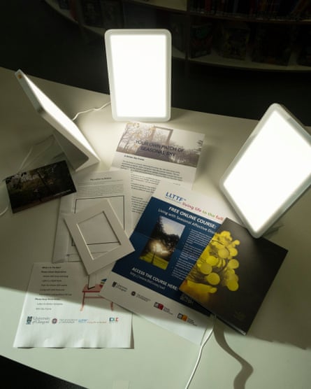 Three upright lamps glow on a table surface, illuminating the leaflets.