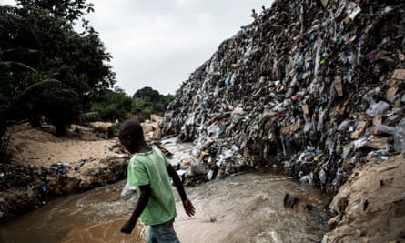 A boy crosses a river whose banks are littered with rubbish in the Kinshasa neighbourhood of Ngaliema.