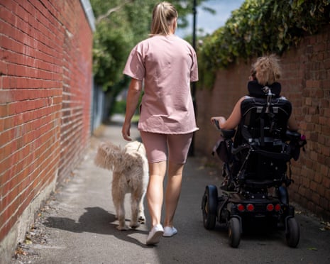 Woman walking a dog alongside another woman in an electric wheelchair.
