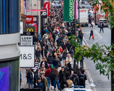 A dense crowd of pedestrians fills Oxford Street, lined with shop signs and traffic