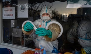 A medical worker prepares to administer a nucleic acid test to a client at a private outdoor clinic in Beijing.