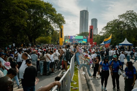 A large crowd gathers in front of a stage in a park