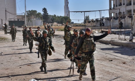 Syrian pro-government soldiers gesture as they walk down a road in eastern Aleppo.