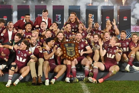 Maroons players celebrate with the trophy.