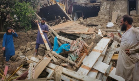 Afghan men search for their belongings in the rubble of a collapsed house.
