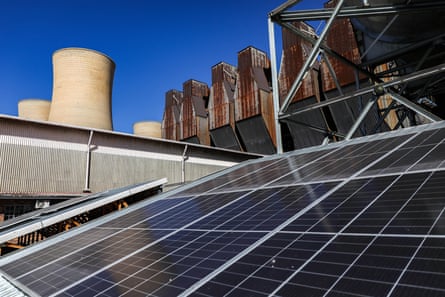 Solar panels on a building with the chimneys of Komati power station in the background