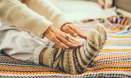 A woman doing stretching exercises wearing colourful wool socks.