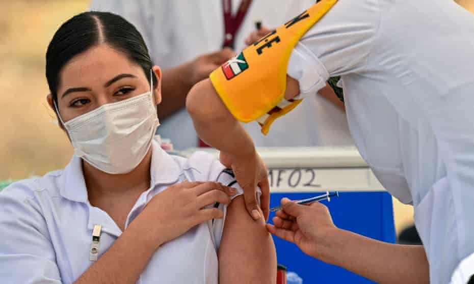 Woman in white uniform and mask receives injection
