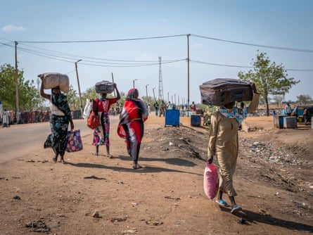 South Sudanese women carry their suitcases across the main road coming from the border with Sudan, in Renk town.