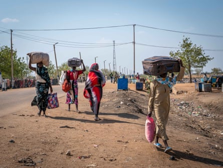 Mujeres sursudanesas cruzan con sus maletas la carretera principal que viene de la frontera con Sudán, en la localidad de Renk.