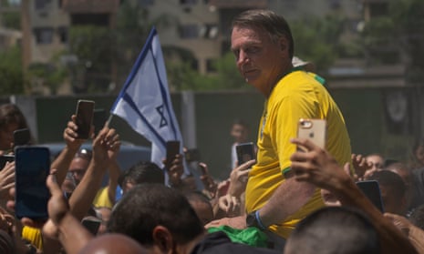a man in a yellow jersey looks backward as people surround him with flags and their phones held high