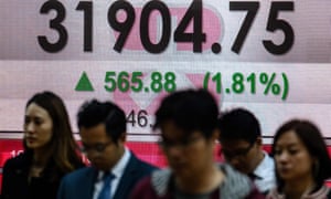 people in Hong Kong walk past the latest Hang Seng index figures