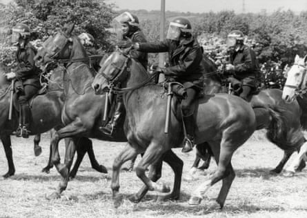 Police officers charging towards the pickets on horseback