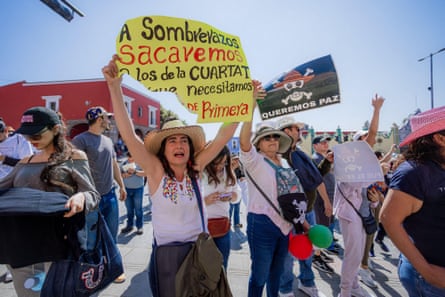 Woman shouting with raised fist during a protest in Puebla, carrying a poster against the Fourth Transformation government and One Piece symbolism