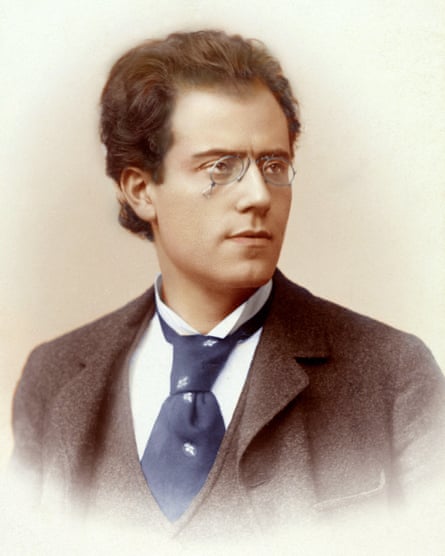 Gustav Mahler, young, with curly hair and round glasses, wears a suit and tie
