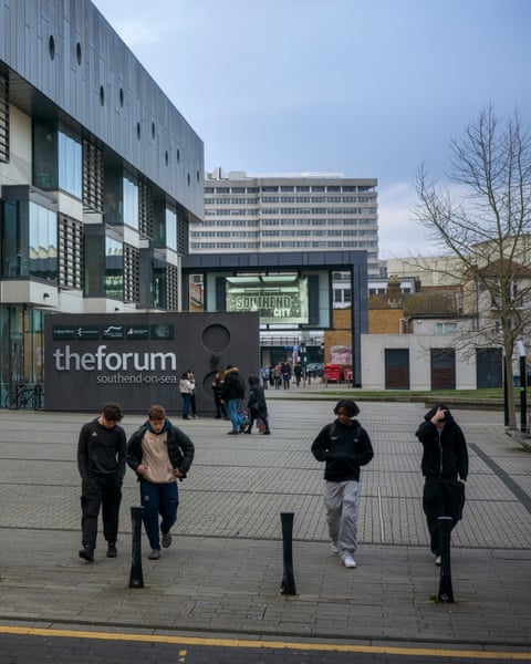 Young people walk across a pedestrian plaza in front of university buildings
