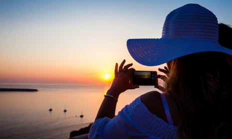 A woman takes pictures of a beautiful sunset