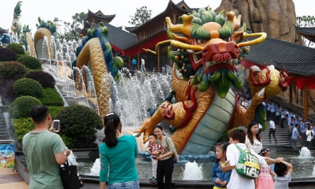 Visitors take photos beside a dragon fountain at Wanda World.