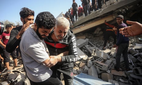 Palestinians help a man injured in an Israeli strike on residential houses in Rafah, in the southern Gaza Strip on Thursday.