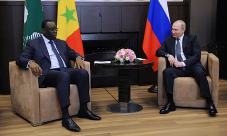 President of Senegal Macky Sall and Russian President Vladimir Putin sit in brown armchairs in front of flags of their respective countries.