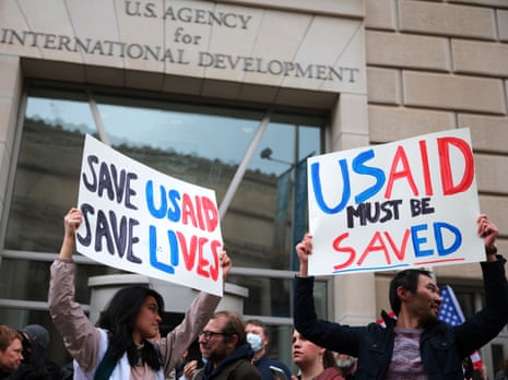 Protesters hold handmade signs reading "Save USAID" outside USAID headquarters
