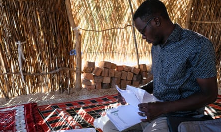 Abdulmonim Adam, a lawyer and human rights monitor, looks through papers in a grass hut