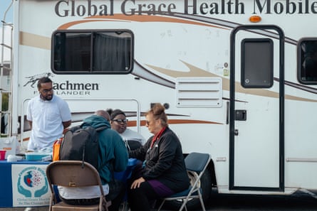 Four people gather around a foldable table in front of a mobile clinic