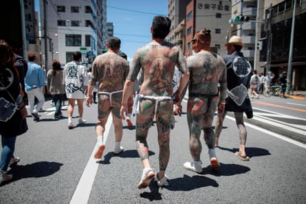 Participants with traditional Japanese tattoos, related to the yakuza, walk through Tokyo during the annual Sanja Matsuri festival.