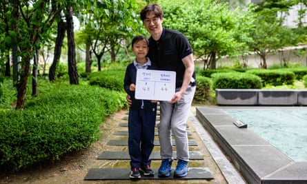 Yoon Jae-ha (left), poses with a whiteboard showing his international age, 8, and Korean age, 9, next to his father, Yoon Dong-gun, in Seoul