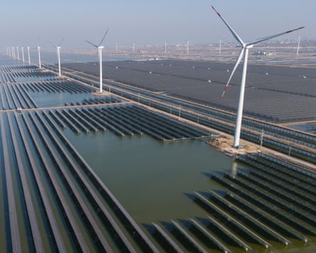 Wind turbines operate along a solar farm