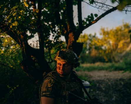 Borya, a shooter from the mobile firing unit of Khyzhak brigade. His face is illuminated by the sun as he stands by a tree.