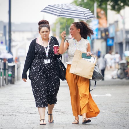 Two young women walk with an umbrella during a spell of rain in Oxford Street