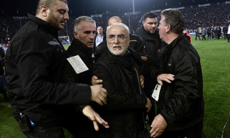 Ivan Savvidis is escorted out after taking to the pitch carrying a handgun in his waistband