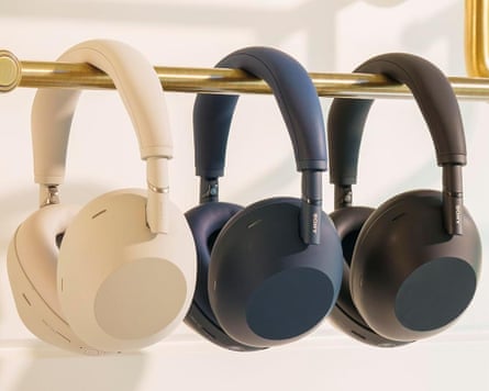 three different colored headphones hanging on gold rack