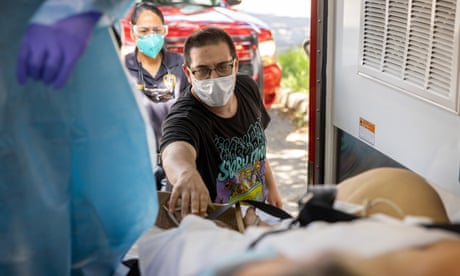A son reaches out to his Covid-positive mother as paramedics prepare to transport her to a hospital in Houston, Texas.