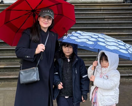 Catherine Cho and her two children by the steps up to the British Museum, with umbrellas