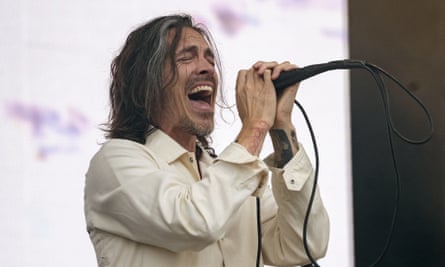 Brandon Boyd of Incubus sings into a microphone while on stage.