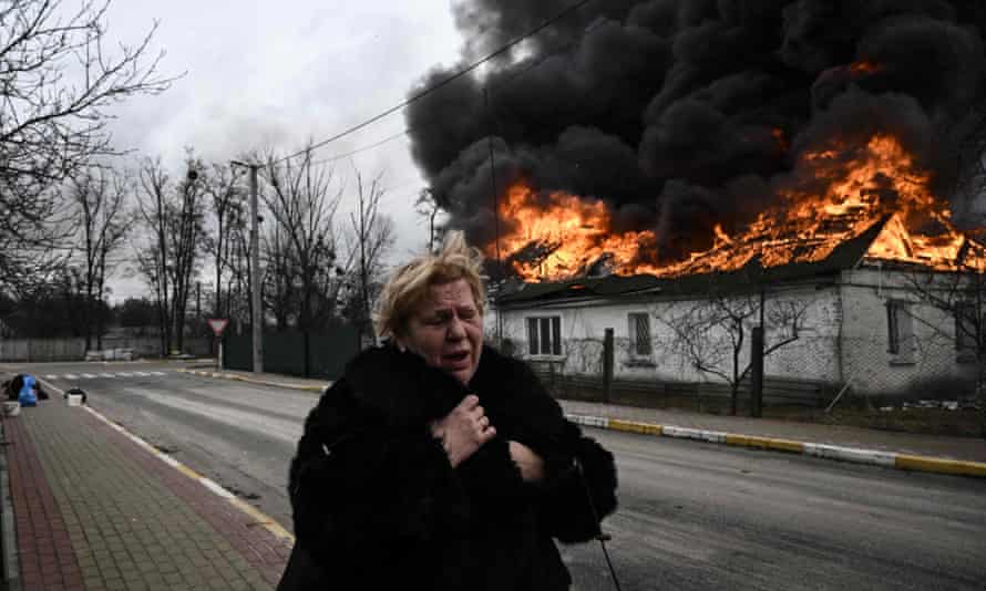 A woman reacts as she stands in front of a house burning after being shelled in the city of Irpin, outside Kyiv.