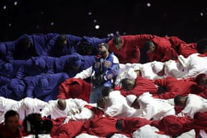 Kendrick Lamar stands in the middle of a group of performers dressed in red, white and blue to resemble the US flag