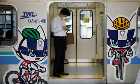 A commuter stands on a train decorated with Tokyo Olympic and Paralympic Games mascots in Tokyo, Japan.