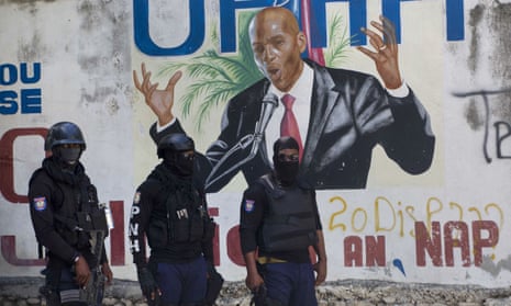 Police stands before a mural of Haiti’s President Jovenel Moïse, who was assassinated last week, days after another 15 Haitians were gunned down.